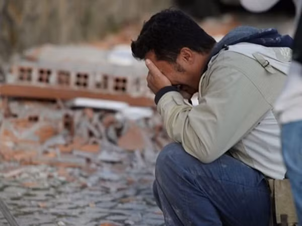 Một người đàn ông ôm mặt khóc bên đống đổ nát tại thị trấn Amatrice. Ảnh:Reuters