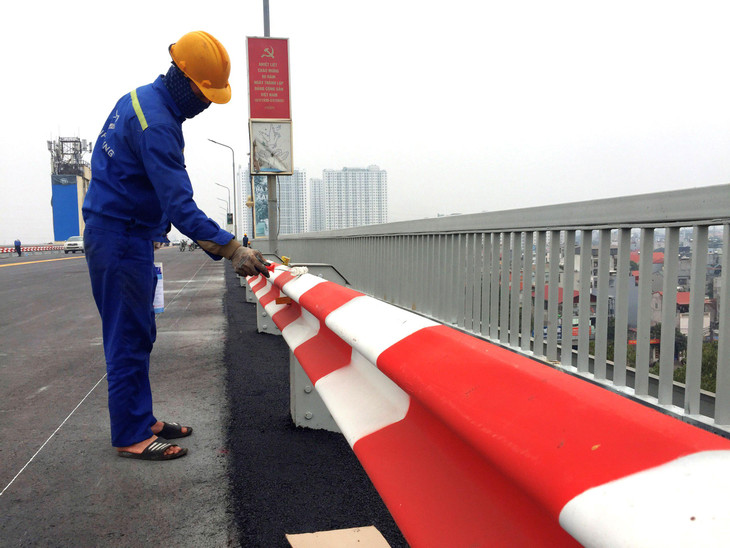 Công nhân sơn lan can cầu và vạch kẻ đường
