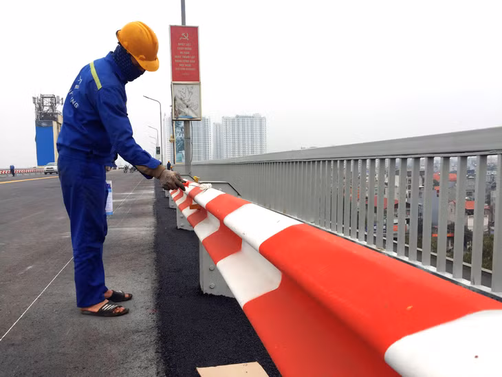 Công nhân sơn lan can cầu và vạch kẻ đường