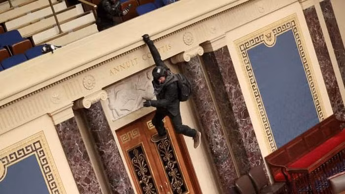 Một người biểu tình đu trên ban công tại khu vực làm việc của Thượng viện - Ảnh: Getty.