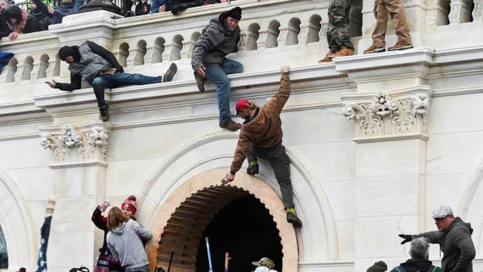 Người biểu tình thân ông Trump trèo tường ở tòa nhà Quốc hội Mỹ ngày 6/1 - Ảnh: Reuters.