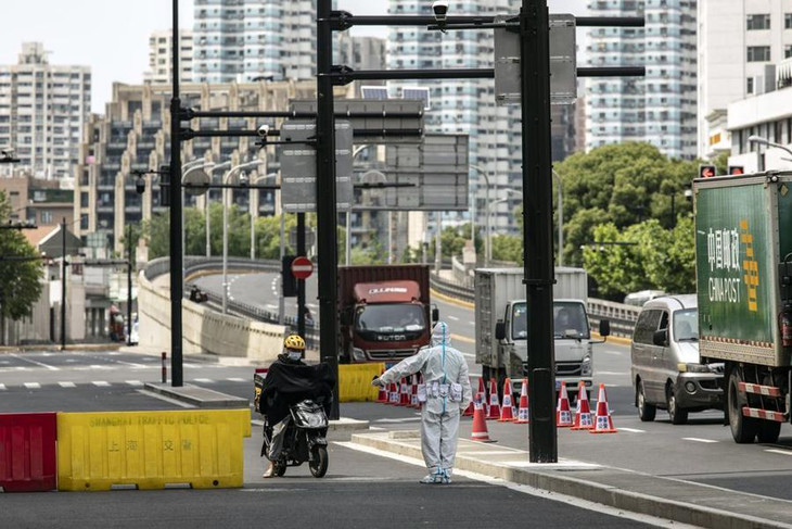Cảnh sát chặn một nhân viên giao hàng đi xe máy tại một trạm kiểm dịch tại Thượng Hải này 18/5 - Ảnh: Bloomberg Cảnh sát chặn một nhân viên giao hàng đi xe máy tại một trạm kiểm dịch tại Thượng Hải này 18/5 - Ảnh: Bloomberg
