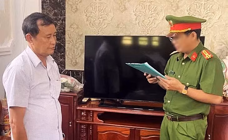 Ông Huỳnh Thế Giới (trái) nghe Công an tỉnh Cà Mau tống đạt quyết định khởi tố bị can