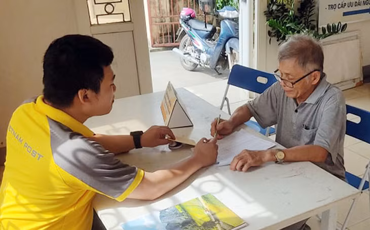 Nhân viên bưu điện hướng dẫn chi trả trợ cấp cho người cao tuổi