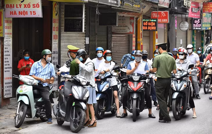 Tại một chốt trên phố Triều Khúc (quận Thanh Xuân), 7h30, lực lượng chức năng kiểm tra giấy thông hành của người đi đường. Dù các phương tiện di chuyển ra vào thường xuyên nhưng không xảy ra tình trạng ùn ứ kéo dài. Khi được dừng lại để kiểm tra giấy tờ, người đi xe máy tập trung thành nhóm đông, thiếu đảm bảo giãn cách.