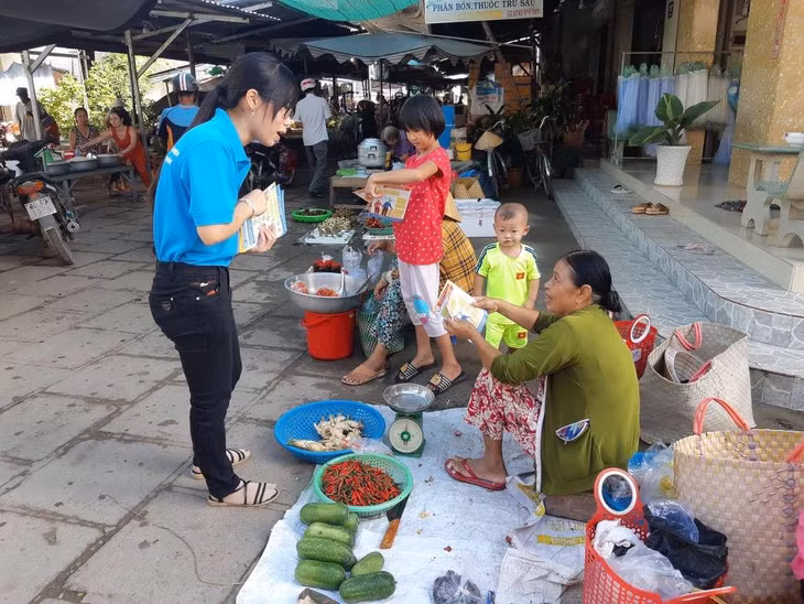 Cán bộ BHXH huyện Trà Cú phát tờ rơi và tuyên truyền cho người dân tại các nhóm chợ