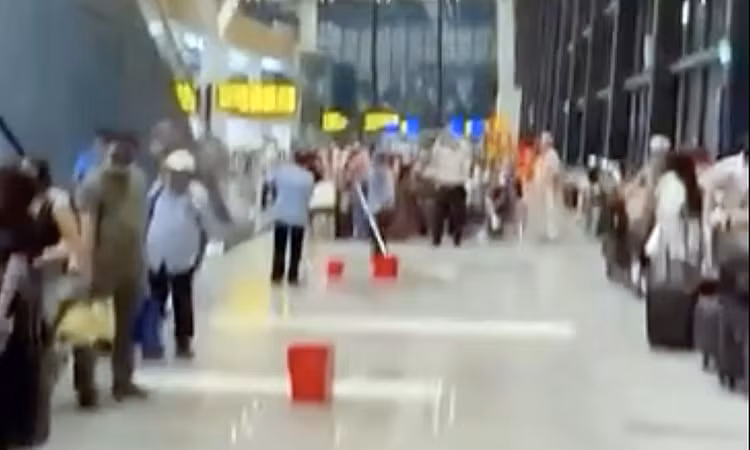 Nhân viên nhà ga dọn dẹp, dùng xô đựng nước trong cơn mưa lớn chiều 7/5. Ảnh: Cắt từ video người dân 