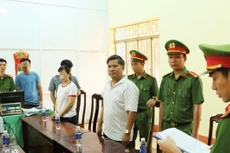 Cơ quan Công an thực hiện lệnh khởi tố bị can và bắt tạm giam đối với Nguyễn Hữu Hóa (áo trắng, bên phải)