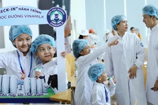 Hai chị em Chip và Bon thích thú chụp ảnh, mặc đồ bảo hộ trước khi tham quan nhà máy sữa của Vinamilk cùng bố mẹ