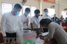 Các hộ dân thuộc diện phải giải tỏa, di dời ký nhận đất tái định cư đã bốc thăm. Ảnh: TTXVN