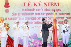 Chủ tịch nước Trần Đại Quang gắn Huân chương Bảo vệ Tổ quốc hạng Nhất lên lá cờ truyền thống của Cục Cảnh sát phòng cháy chữa cháy. (Ảnh: Nhan Sáng/TTXVN)