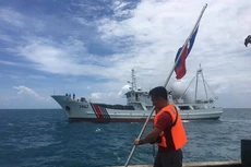 Một nhà hoạt động Philippines cầm quốc kỳ khi tàu hải cảnh Trung Quốc áp sát ở bãi cạn Scarborough, cách đảo chính Luzon của Philippines 230 km, tháng 6/2016. Ảnh:AFP.