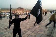 Một tay súng cầm cờ IS trên đường phố Mosul sau khi nhóm chiếm giữ thành phố hồi tháng 6/2014. Ảnh: Reuters