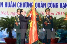 Chủ tịch nước Trần Đại Quang gắn Huân chương Quân công hạng Nhất lên lá cờ truyền thống của lực lượng vũ trang Thủ đô. (Ảnh: Nhan Sáng/TTXVN)