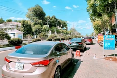 Dọc tuyến đường Hùng Vương - một tuyến đường trung tâm của huyện này - ô tô nối tiếp nhau thành dãy dài trước các văn phòng công chứng. Ảnh: Ngô Bảo Tín