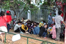 Các công nhân ngồi chờ đợi thông tin phía trước cổng doanh nghiệp