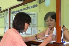 Hướng dẫn thủ tục cho người dân tại bộ phận một cửa Văn phòng Đăng ký đất đai Hà Nội. (Ảnh: Đỗ Phương Anh/TTXVN)