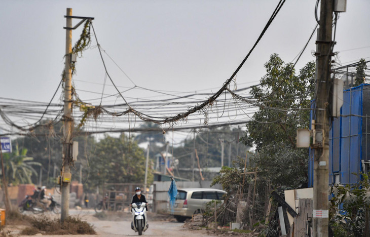 Nhiều cột điện và hệ thống dây chằng chịt nằm giữa đoạn đường chưa hoàn thiện tiềm ẩn nguy hiểm cho người qua lại, nhất là trong những ngày mưa gió.