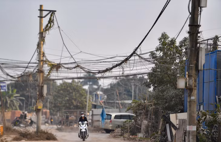 Nhiều cột điện và hệ thống dây chằng chịt nằm giữa đoạn đường chưa hoàn thiện tiềm ẩn nguy hiểm cho người qua lại, nhất là trong những ngày mưa gió.