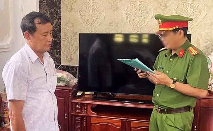 Ông Huỳnh Thế Giới (trái) nghe Công an tỉnh Cà Mau tống đạt quyết định khởi tố bị can