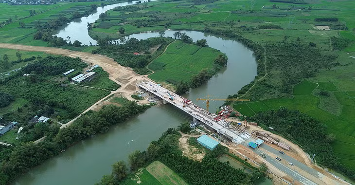 Cầu Quảng Đà đã thành hình, trong đó phía Đà Nẵng (bìa phải) đang lu lèn chuẩn bị thảm nhựa đường dẫn, phía Quảng Nam mới tạo mặt bằng đất