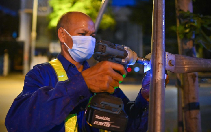 Công nhân Công ty Công viên cây xanh Hà Nội dùng súng bắn ốc tháo dỡ hệ thống khung đỡ.