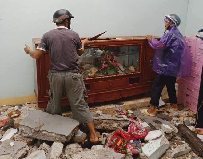 Người dân thu dọn đồ đạc, dọn dẹp các đống gạch sau khi vách tường bị đổ sập.