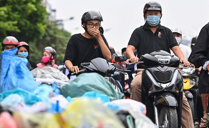 Người đi đường bịt mũi khi lưu thông qua những đống rác đổ ven đường Tây Sơn