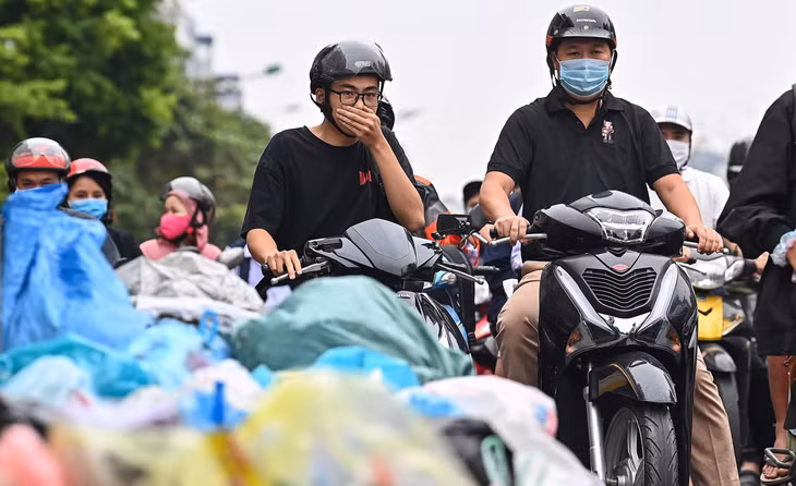 Người đi đường bịt mũi khi lưu thông qua những đống rác đổ ven đường Tây Sơn