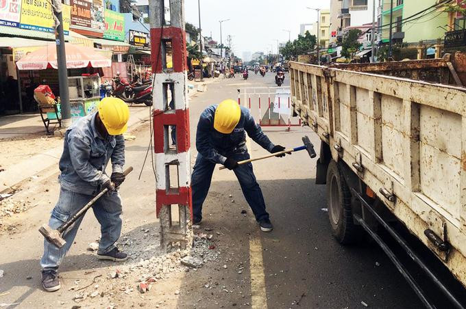 Nhân viên điện lực dùng búa đập móng trụ điện để di dời
