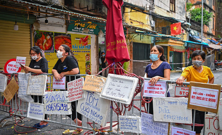 Khu vực chợ đầu phố Cầu Gỗ, lực lượng chức năng đã lập hàng rào chặn lối đi để hạn chế người dân ra đường. Nhưng tại đây, trên rào chắn lại được treo kín mít bởi những tấm biển quảng cáo bằng nhiều chất liệu, được ghi đầy đủ thông tin mặt hàng kèm số điện thoại để người tới mua có thể liên hệ và nhận hàng.