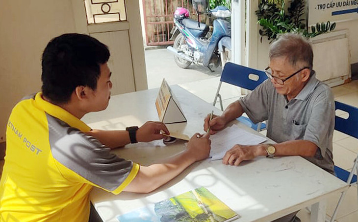 Nhân viên bưu điện hướng dẫn chi trả trợ cấp cho người cao tuổi