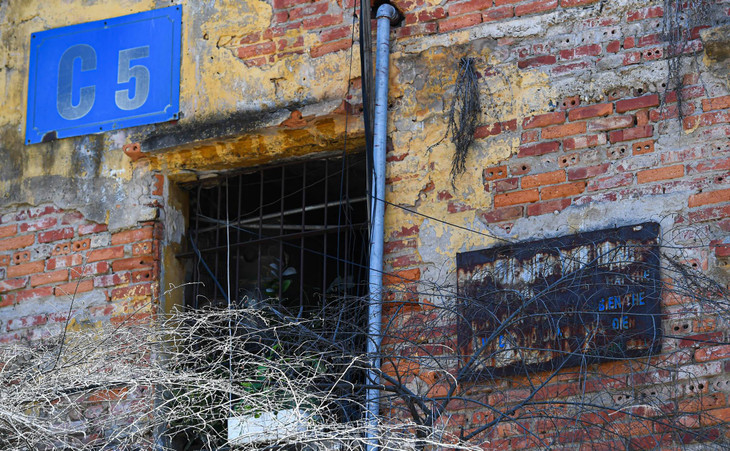 Trải qua hơn 60 năm tồn tại, nhiều lớp tường đã bóc tróc lộ ra lớp gạch cũ kỹ, tấm biển tên khu tập thể hoen gỉ không còn nhìn rõ chữ.