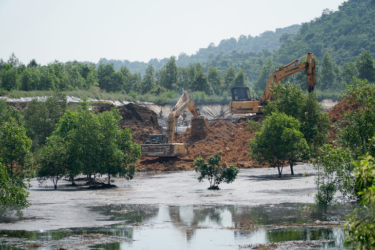Hai xe múc đắp đoạn bờ bao hồ chứa bị vỡ
