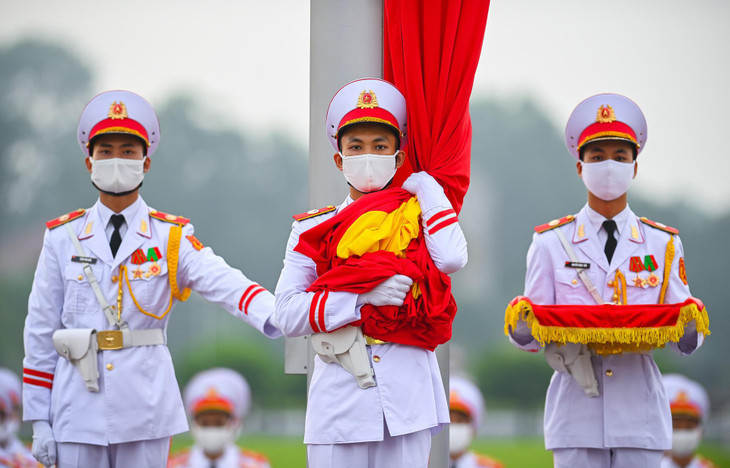 3 chiến sĩ của đội hồng kỳ nghiêm trang bước lên bục để chuẩn bị thực hiện các nghi thức chính. Lúc 5h59, chiến sĩ mang Quốc kỳ treo lên cột cờ