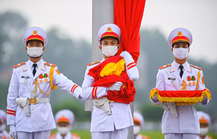 3 chiến sĩ của đội hồng kỳ nghiêm trang bước lên bục để chuẩn bị thực hiện các nghi thức chính. Lúc 5h59, chiến sĩ mang Quốc kỳ treo lên cột cờ