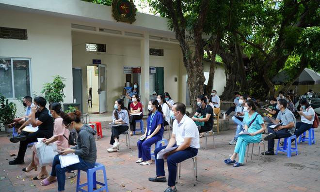 Hình ảnh người dân ngồi xếp hàng để đến lượt được cấp giấy đi đường có mã QR ở Hà Nội