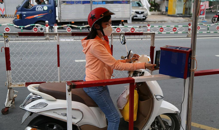 Người đi đường đưa điện thoại để quét mã QR ở chốt đường Phan Đăng Lưu, quận Phú Nhuận Người đi đường đưa điện thoại để quét mã QR ở chốt đường Phan Đăng Lưu, quận Phú Nhuận