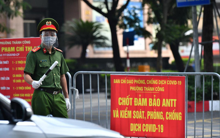 Thượng uý Lê Anh Dũng làm nhiệm vụ rà soát giấy người đi đường tại một chốt trên phố Giảng Võ. Tuy nhiên, để tránh tình trạng bị ùn ứ ở đầu chốt vào sáng thứ hai đầu tuần, nhiều chốt chặn phải nhanh chóng để cho xe đi qua.