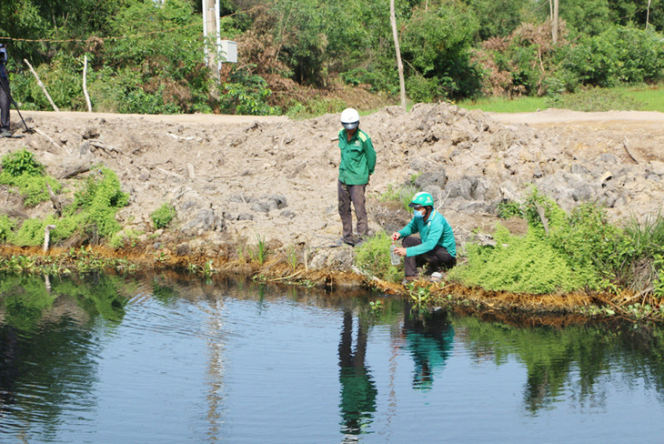 Lực lượng chức năng lấy mẫu nước dưới dòng kênh bị ô nhiễm do nước thải của Công ty TNHH An Hưng Nông