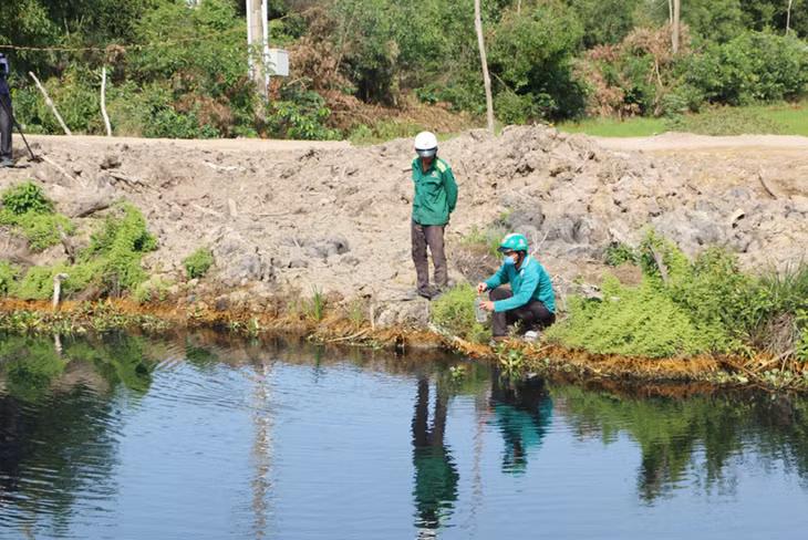Lực lượng chức năng lấy mẫu nước dưới dòng kênh bị ô nhiễm do nước thải của Công ty TNHH An Hưng Nông