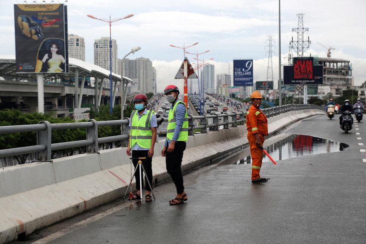 Kỹ sư đến đo đạc, kiểm tra trên cầu vượt Nguyễn Hữu Cảnh tại đoạn mặt cầu bị võng xuống, đọng nước
