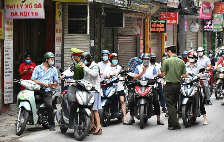 Tại một chốt trên phố Triều Khúc (quận Thanh Xuân), 7h30, lực lượng chức năng kiểm tra giấy thông hành của người đi đường. Dù các phương tiện di chuyển ra vào thường xuyên nhưng không xảy ra tình trạng ùn ứ kéo dài. Khi được dừng lại để kiểm tra giấy tờ, người đi xe máy tập trung thành nhóm đông, thiếu đảm bảo giãn cách.