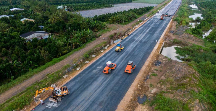 Xe lu gia cố mặt bê tông nhựa. Theo chủ đầu tư, dự án hiện đạt 85% tiến độ, 34/34 gói thầu được thi công. Cao tốc sẽ được hoàn thiện trước Tết Nguyên đán 2022.