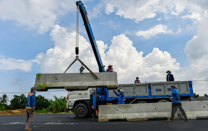 Công nhân lắp đặt dải phân cách sau khi mặt đường hoàn thiện.