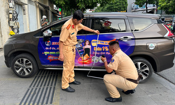 Cảnh sát giao thông kiểm tra một xe dán quảng cáo với nội dung cá độ
