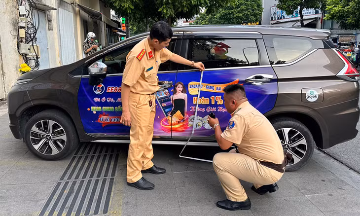 Cảnh sát giao thông kiểm tra một xe dán quảng cáo với nội dung cá độ
