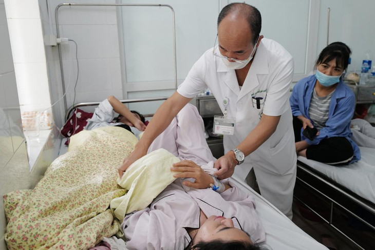 Bệnh nhân sốt xuất huyết nằm ghép hai người một giường, đảo đầu nằm, tại Trung tâm Bệnh nhiệt đới, Bệnh viện Bạch Mai