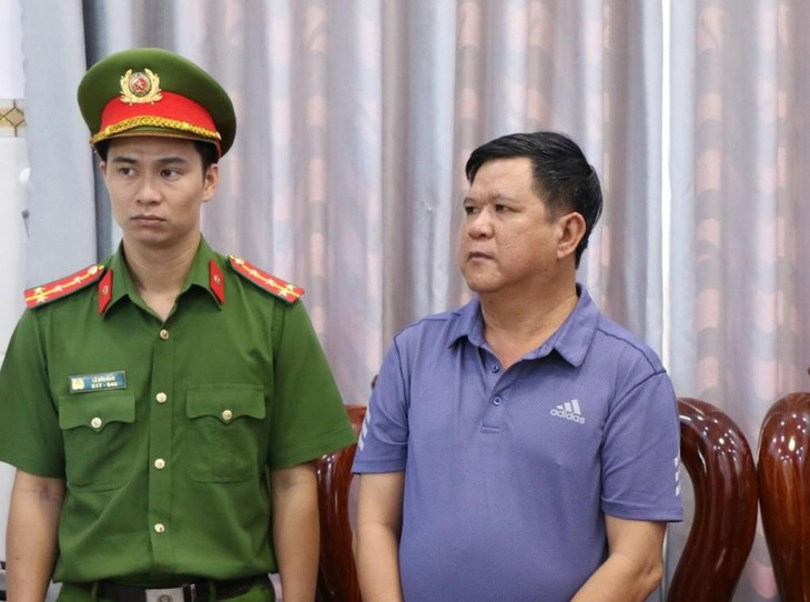 Hoàng Văn Phi (phải) nghe đọc lệnh bắt tạm giam