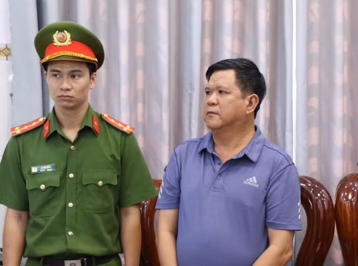 Hoàng Văn Phi (phải) nghe đọc lệnh bắt tạm giam